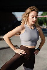 Fototapeta premium Young woman in athletic wear posing outdoors with hands on hips