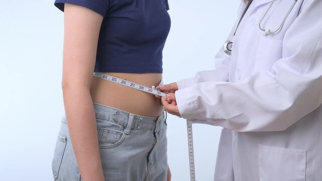 Professional doctor uses measuring tape to check happy patient slim waist during clinic consultation for healthy weight loss journey