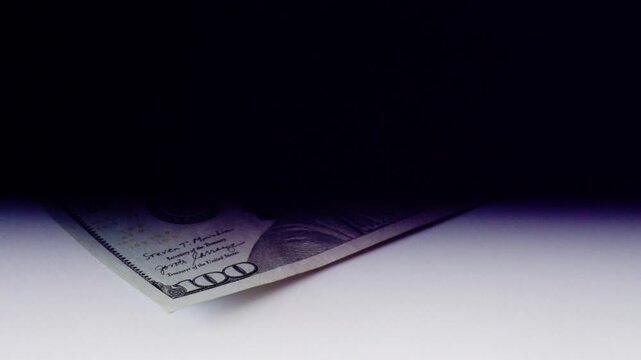 Lowangle hidden hundreddollar bill under black shadow on floor, underground profit scene bill peeking from darkness, dramatic contrast, hush tone, emphasis on concealment