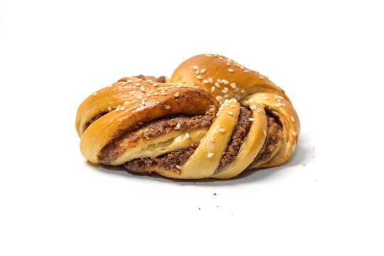 Side view of a freshly baked twisted pastry bun filled with chocolate or nut paste and sprinkled with white sesame seeds.