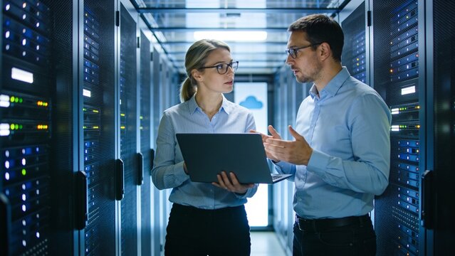 Multiethnic IT professionals monitoring server racks and network security in modern data center.