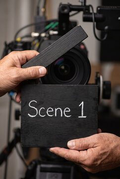 Crew member holding a Scene 1 clapperboard before filming