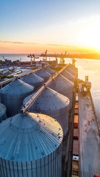 Aerial view captures a storage facility at sunrise, alongside a body of water and a port with cranes