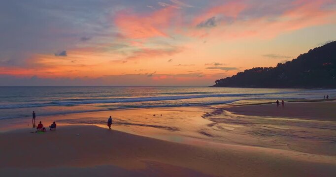 Aerial view The beach glows under the vibrant sunset, where streaks of crimson and tangerine stretch across the sky. Waves roll in, foaming and glistening as the sun&rsquo;s last light kisses their crests
