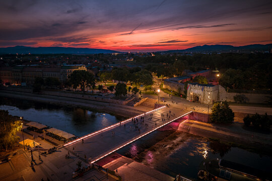 Evening scene near the Nisava river with people walking and a city fortress in the background
