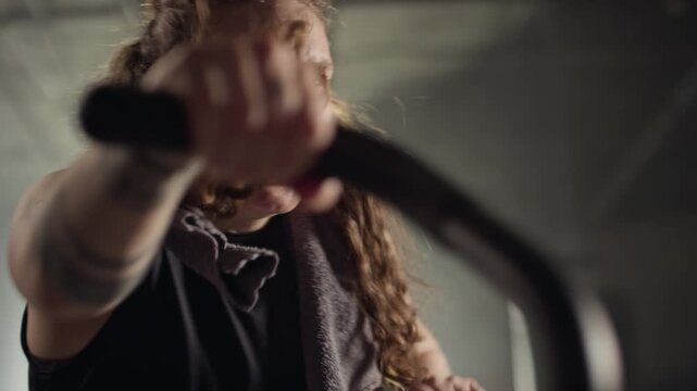 Young Caucasian woman exercising intensely on air bike in gym. Clip is ideal for fitness brand advertisements, gym promotions, and motivational health campaigns