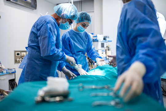 Surgeons performing operation in hospital. Medical team during surgical procedure, Healthcare and medicine concept. Professional doctors in blue scrubs working together in operating room.