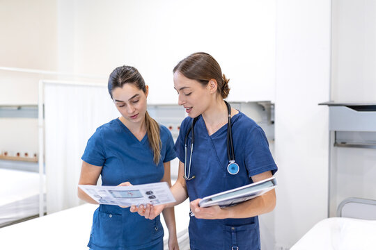 Nurses reviewing medical notes. Healthcare professionals holding paper chart and folder in hospital ward, Medical staff talking about patient treatment plan and diagnosis.