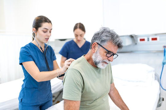 Doctor examining patient with stethoscope. Senior man sitting on hospital bed while medical professional checks his back, Healthcare and medicine checkup concept in clinic.