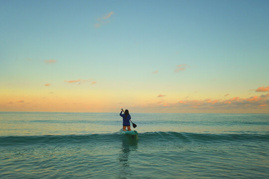 Person on a paddleboard in the ocean at dawn