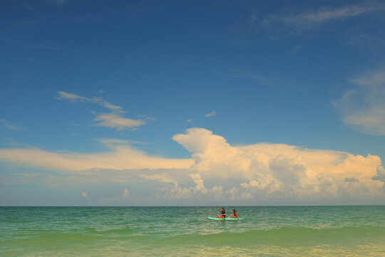 Two people paddleboarding under a big blue sky