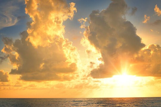 Golden sunset light illuminates clouds over sea