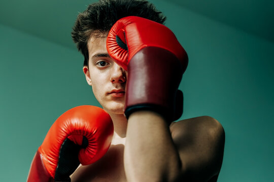 Teenage boxer looks at camera with gloves up