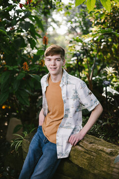 A smiling teenage boy in a lush tropical garden
