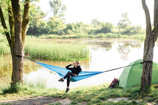 Sport girl lying on hammock on meadow near lake