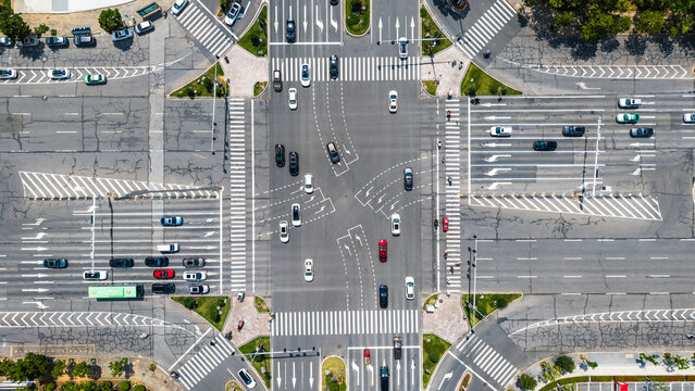 Aerial view of urban crossroad with heavy vehicle traffic and pedestrian crossings
