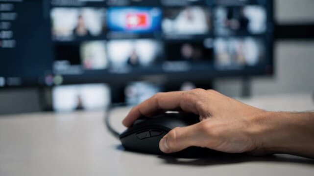 Focused view of a moderators hands using a mouse over a livestream content queue dashboard the main flagged stream thumbnail sharp while the rest fade into soft blur.