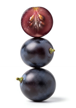 A three dark purple grapes stacked vertically, with the top grape sliced in half to reveal the interior, isolated on a pure white background