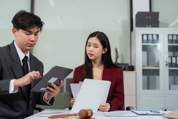 legal counsel reviewing paperwork at a desk in an office, working with a tablet on law and justice...