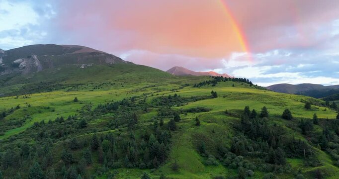 Time-lapse footage of rainbow over alpine pasture on Genie South Line, Sichuan China, green grassland and rolling hills under cloudy twilight sky, western Sichuan plateau scenery