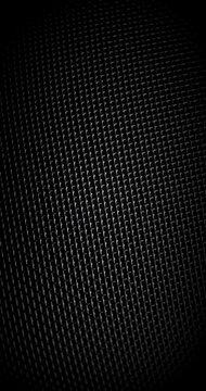 Fast Rotating Black Metal Mesh. Dark woven grid spins rapidly under narrow directional light, revealing reflective highlights and repeating geometric structure.
