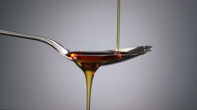 Golden Honey Pouring into Spoon in Slow Motion Close Up with Smooth Flow and Rich Amber Texture