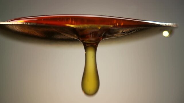 Golden Honey Dripping from Metal Spoon in Slow Motion with Smooth Flow