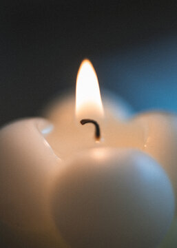 Burning white candle with warm flame and dark copy space