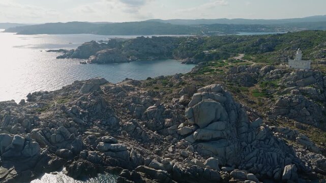 Cinematic drone flight over Capo Testa in northern Sardinia, revealing its lighthouse, massive granite formations, secluded coves and shimmering Mediterranean Sea.