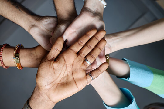 Close up of diverse adult hands stacking together, symbolizing teamwork, unity, collaboration in workplace. Ideal for corporate culture, inclusion, partnership messaging