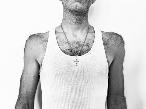 Studio shot of man in tank top with crucifix on chain, black and white