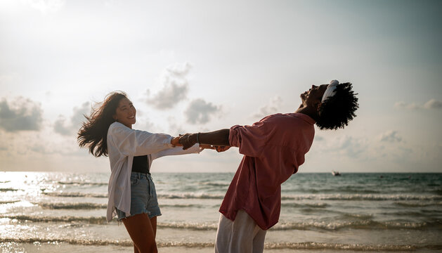 Happy couple having fun at the beach, playing and laughing together in a romantic tropical setting
