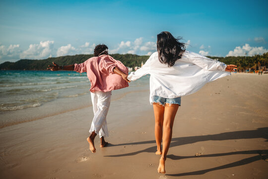 Diverse pair of friends, couple laughing together in a scenic coastal environment