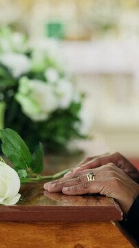 Funeral, flower and hands of widow on coffin for grief, mourning death or final goodbye in church. Partner loss, person or rose on casket at burial service for farewell, sorrow or respect at memorial