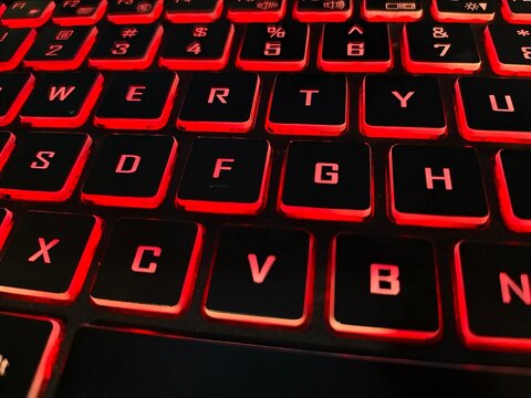 Close-up view of qwerty laptop keyboard keys with red led backlighting keyboard computer alphabet