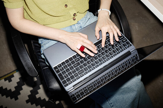 Overhead shot of woman typing on laptop while sitting in office chair, working remotely and managing digital tasks. Ideal for remote work or productivity marketing