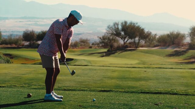 A golfer compresses an iron shot on par 3 and sends divot spray flying in warm golden light on a desert course, captured in slow motion. Strong for premium golf promos.