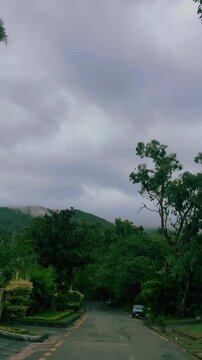 Vertical Street View of Islamabad with Margalla Hills and Lush Greenery Under Cloudy Sky