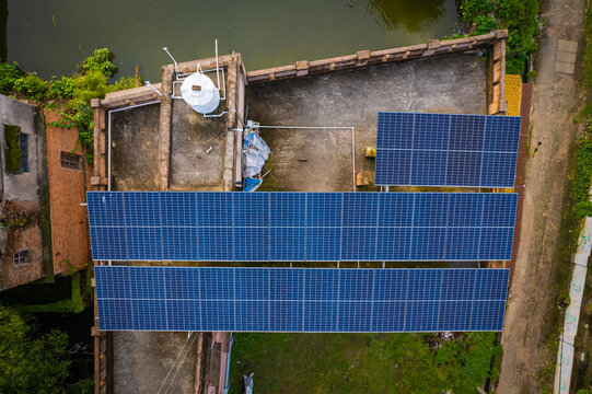 Top Down Drone View of Rooftop Solar Panels on Residential Building in Green Urban Neighborhood  