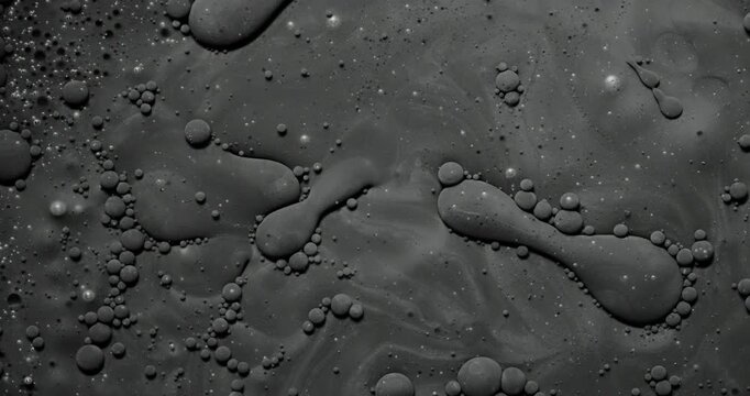 	
Abstract dark fluid texture. Macro view of viscous gray liquid with bubbles and organic swirls, slow gentle flow creating glossy reflections.
