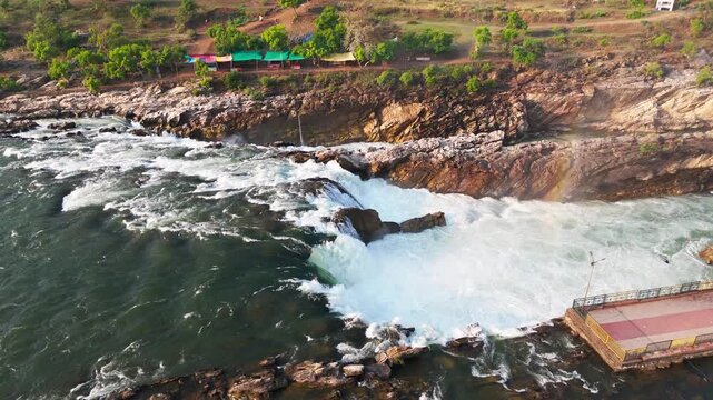 Smooth DJI Air 3 drone orbit from left to right, revealing the powerful Dhuandhar Waterfall and Narmada River at Bhedaghat, Jabalpur, Madhya Pradesh, India during early morning in late March.