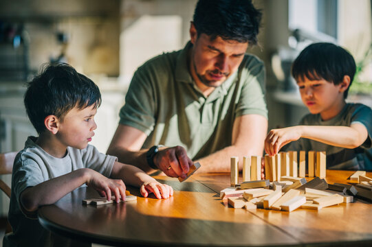 Father and sons playing with wooden blocks at home