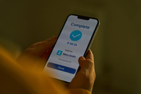 Hand holding smartphone showing completed online payment indoors
