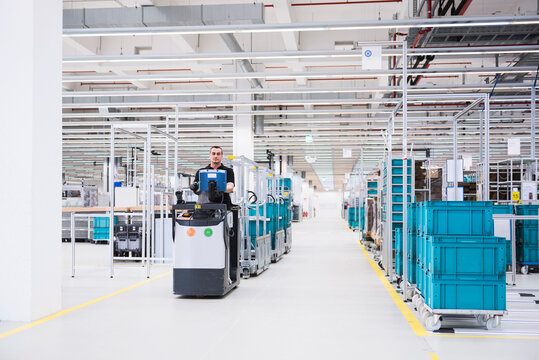 Man driving a tugger train in factory shop floor