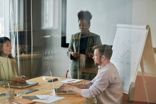 Business colleagues conducting meeting seen through glass wall in office