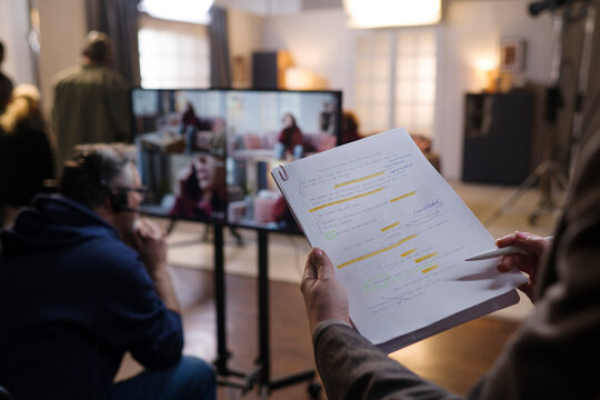 Director holds a script while filming on a production set indoors