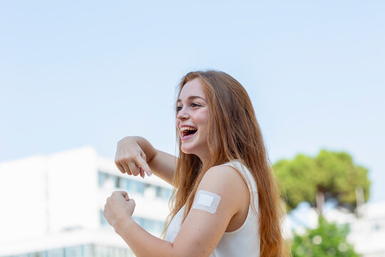 Cheerful female professional pointing at bandage after taking vaccine during pandemic