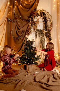 Siblings decorating a Christmas tree in a cozy festive studio