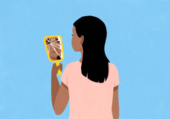 Young woman looking at reflection of her face in cracked vanity mirror against blue background
