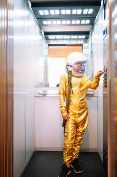 Boy wearing space suit pressing buttons in open elevator